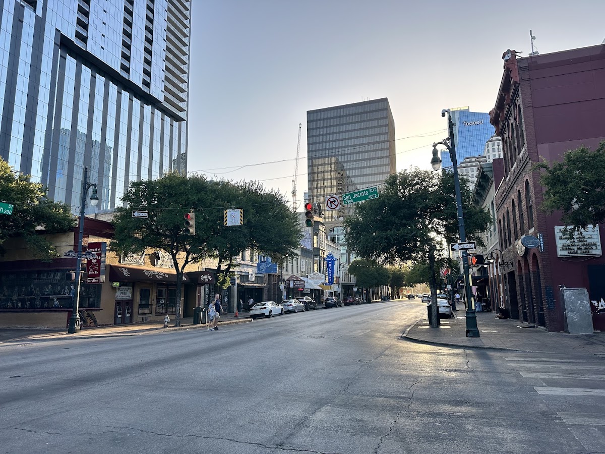 Concrete safety barriers lining East 6th Street in Austin with cars driving through on a weekend night
