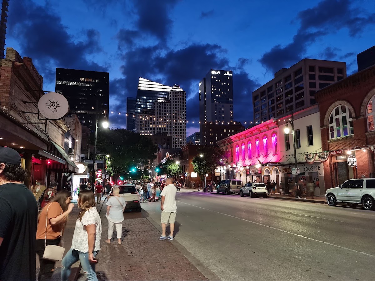 Neon signs and a busy crowd on East 6th Street in downtown Austin at night