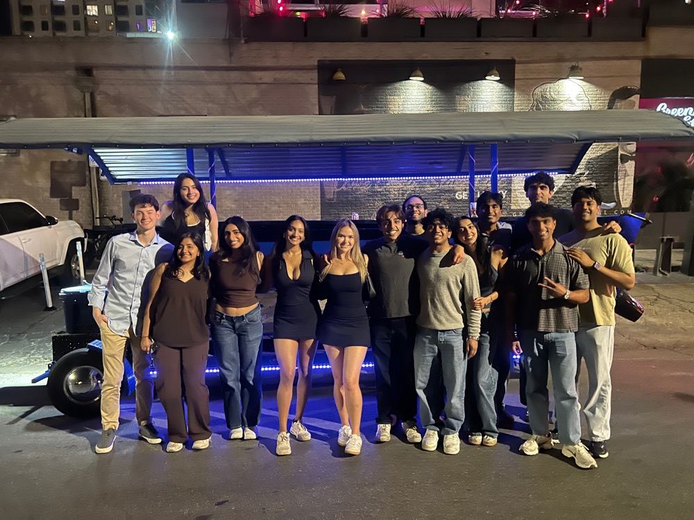A large group of friends by the party bike downtown at night