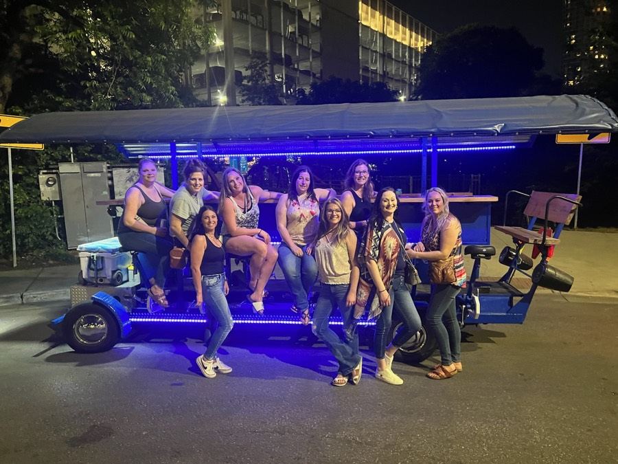 Friends posing by the party bike lit up at night