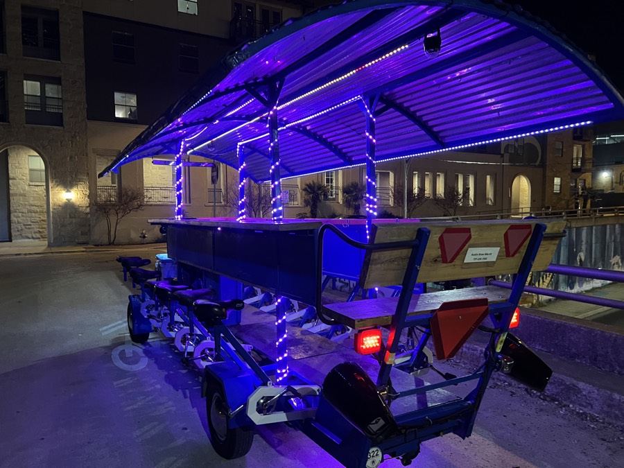 The party bike glowing purple under its LED lights on a downtown Austin night