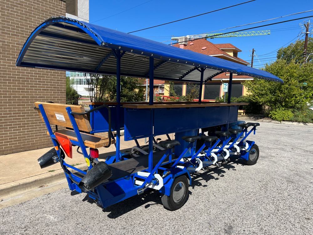 The blue 15-seat Austin Bar Bike parked in the daylight, side on