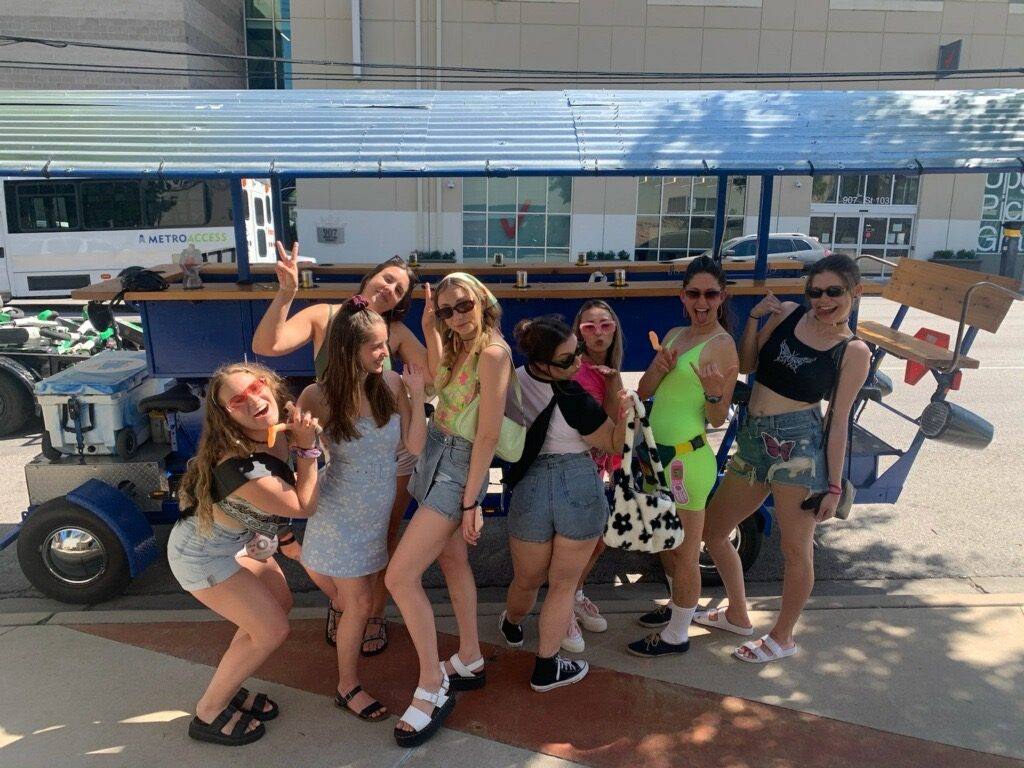 Bachelorette party cheering aboard the party bike with the downtown Austin skyline behind them