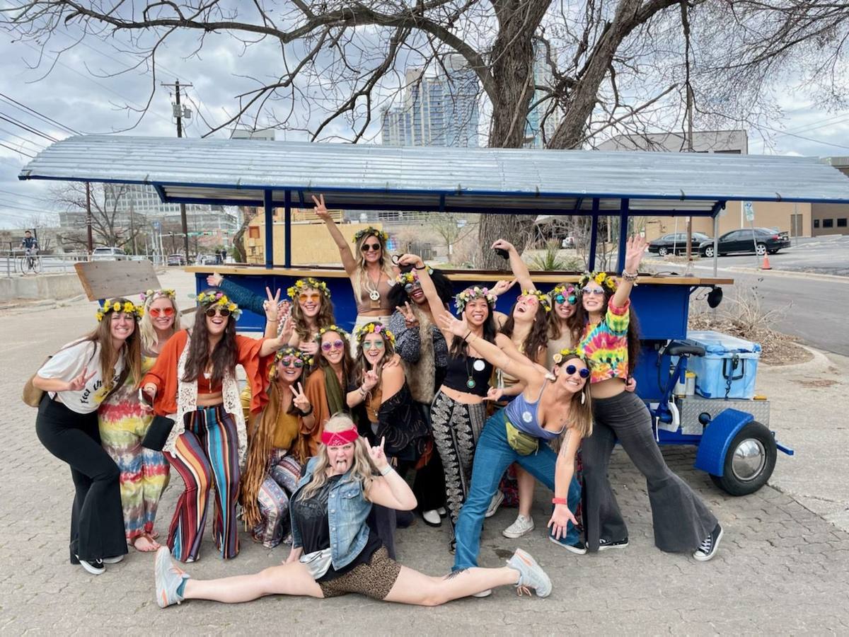 A themed bachelorette group posing with the party bike on 6th Street