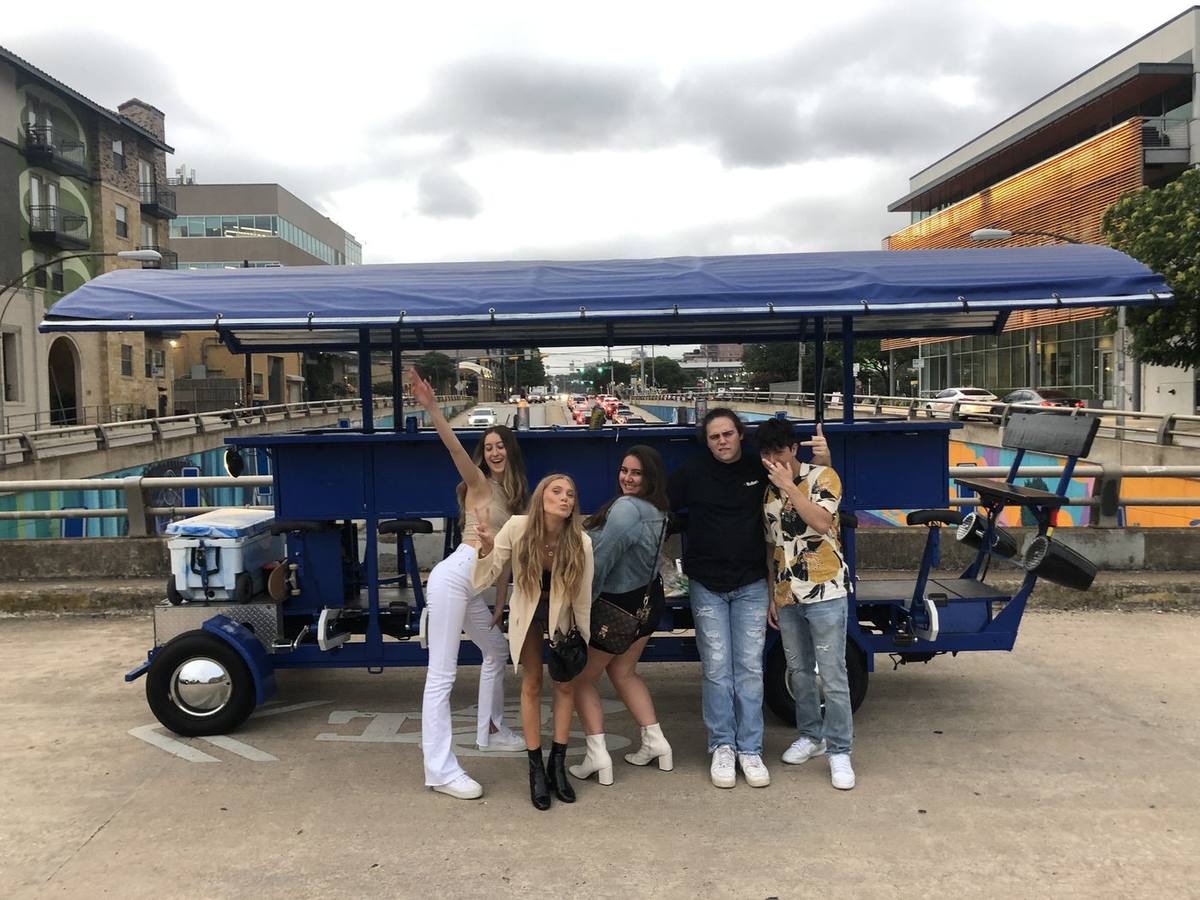 Team photo with the party bike in front of a colorful Austin mural