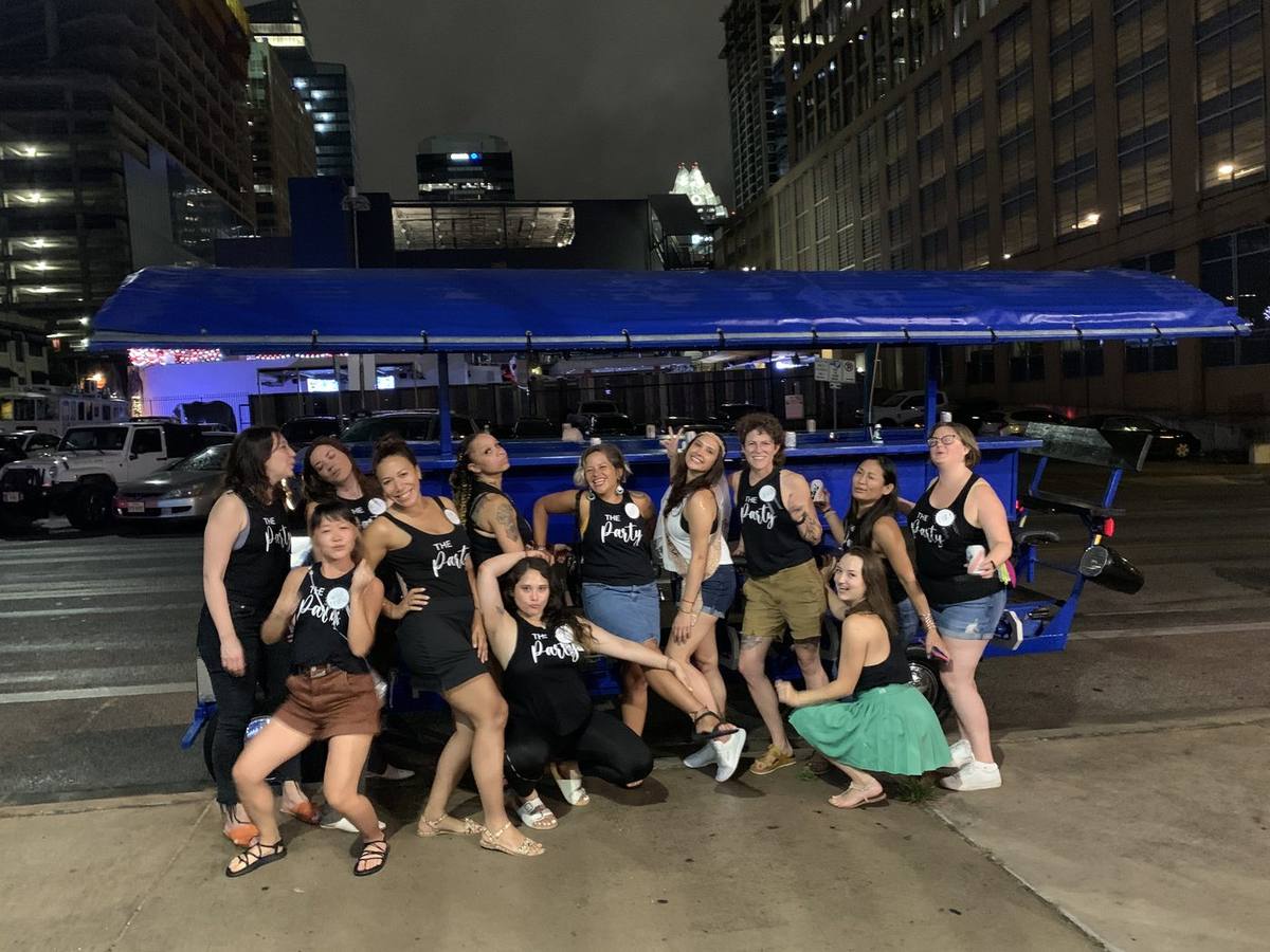 A bachelorette group riding the blue party bike through downtown Austin