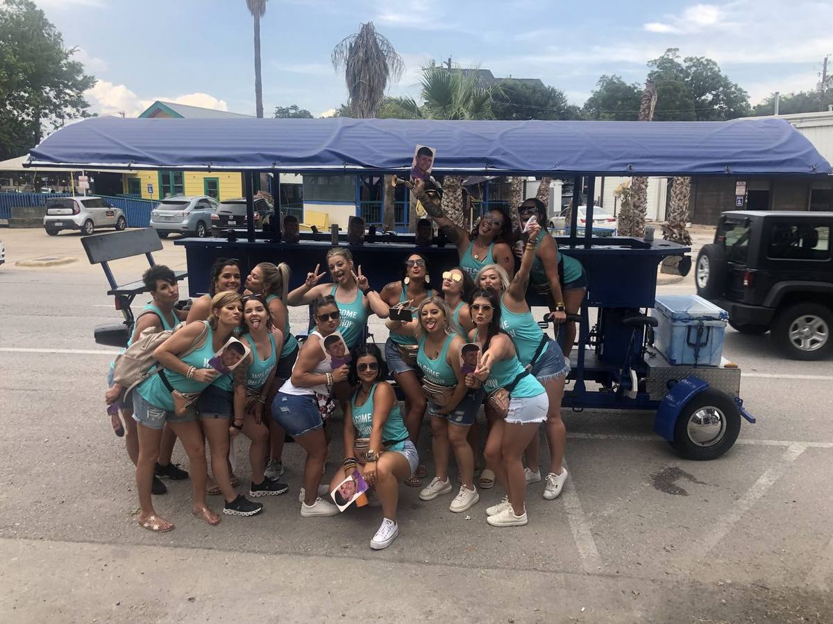 A bachelorette group riding the blue party bike through downtown Austin