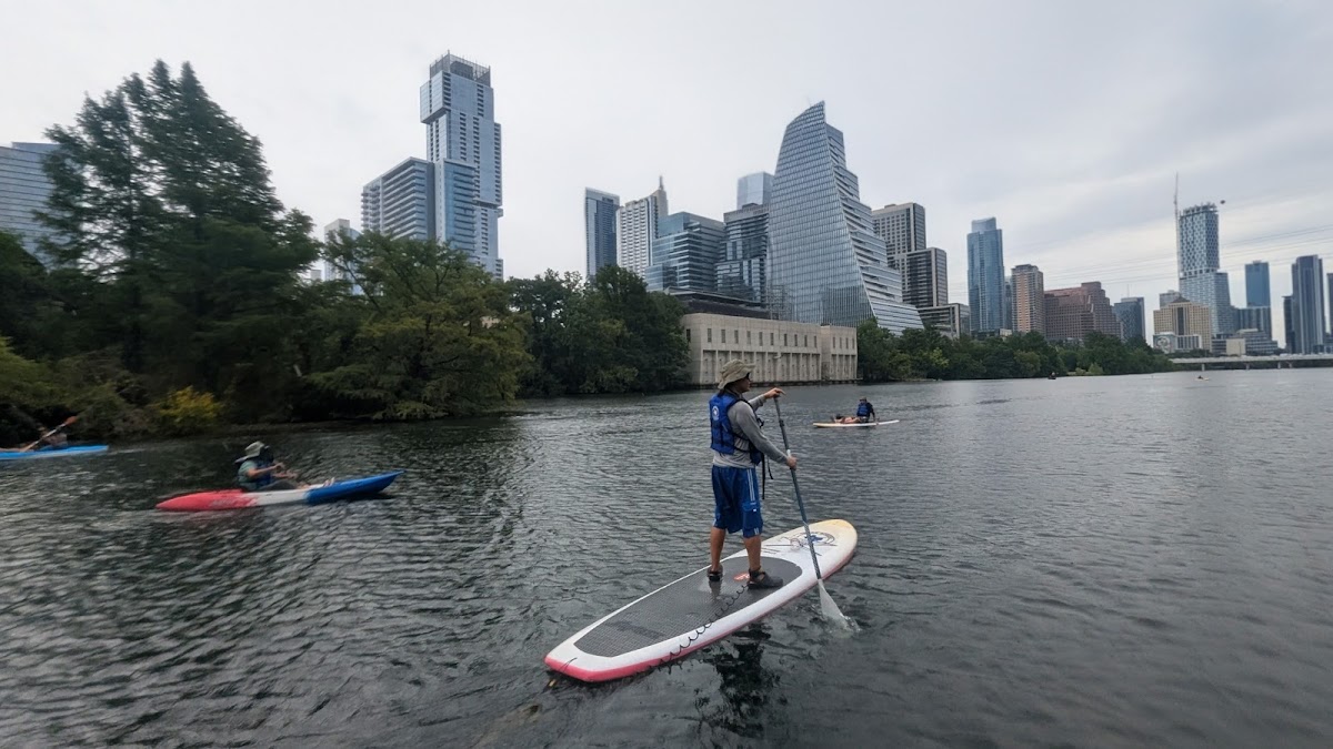 Paddleboarders on Lady Bird Lake with the downtown Austin skyline behind them