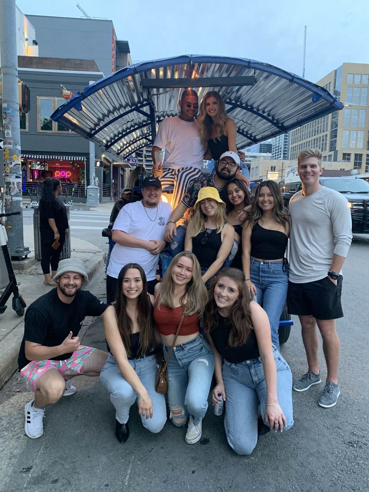 Group of friends posing in front of the Austin Bar Bike downtown at dusk