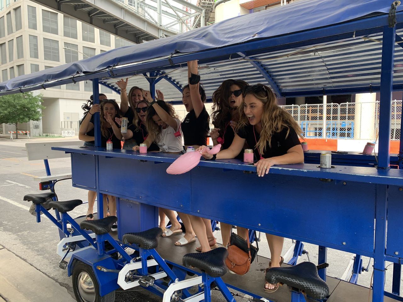 A group cracking up on the blue Austin Bar Bike as it rolls through downtown Austin