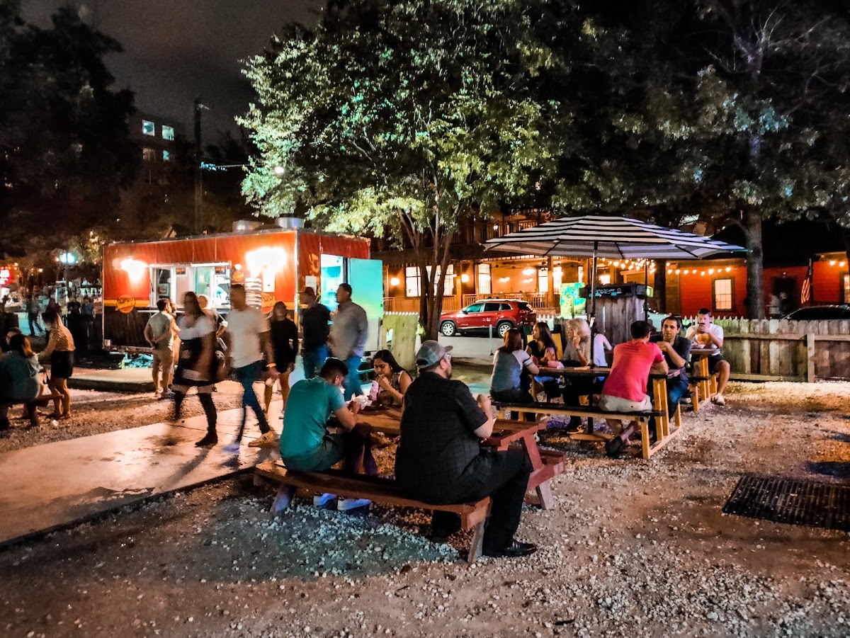 Converted bungalow bars with string lights along Rainey Street in downtown Austin at dusk