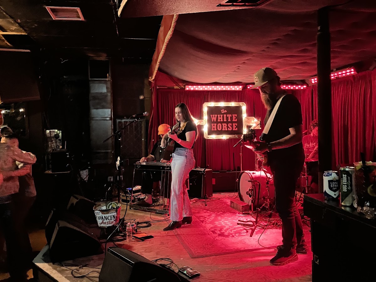 A live band playing under red lights at The White Horse honky tonk in East Austin